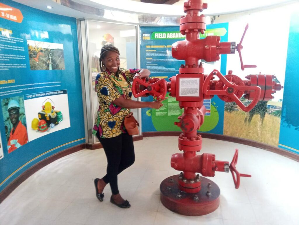 Sarah standing next to a large red industrial structure nicknamed the "Christmas Tree," which is part of an exhibit on Uganda's energy development.