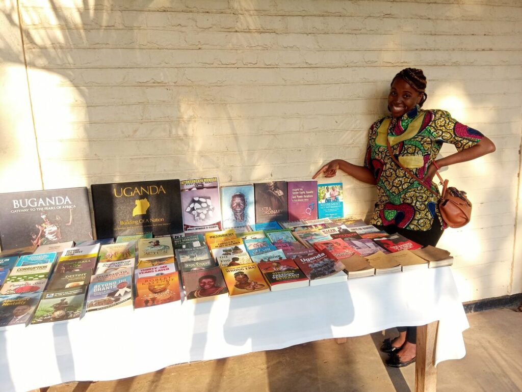 Sarah standing at a table covered in books and informational materials at the entrance of the Uganda Museum.