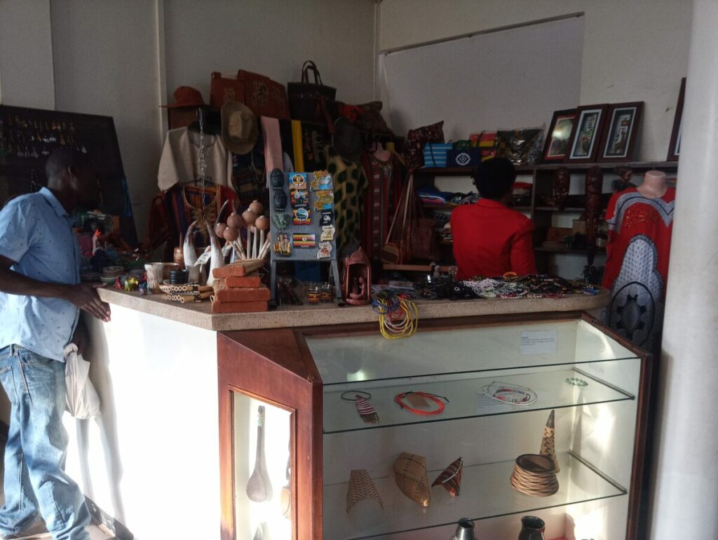 The reception desk at the entrance of the Uganda Museum, featuring glass display cases filled with artifacts and informational materials.