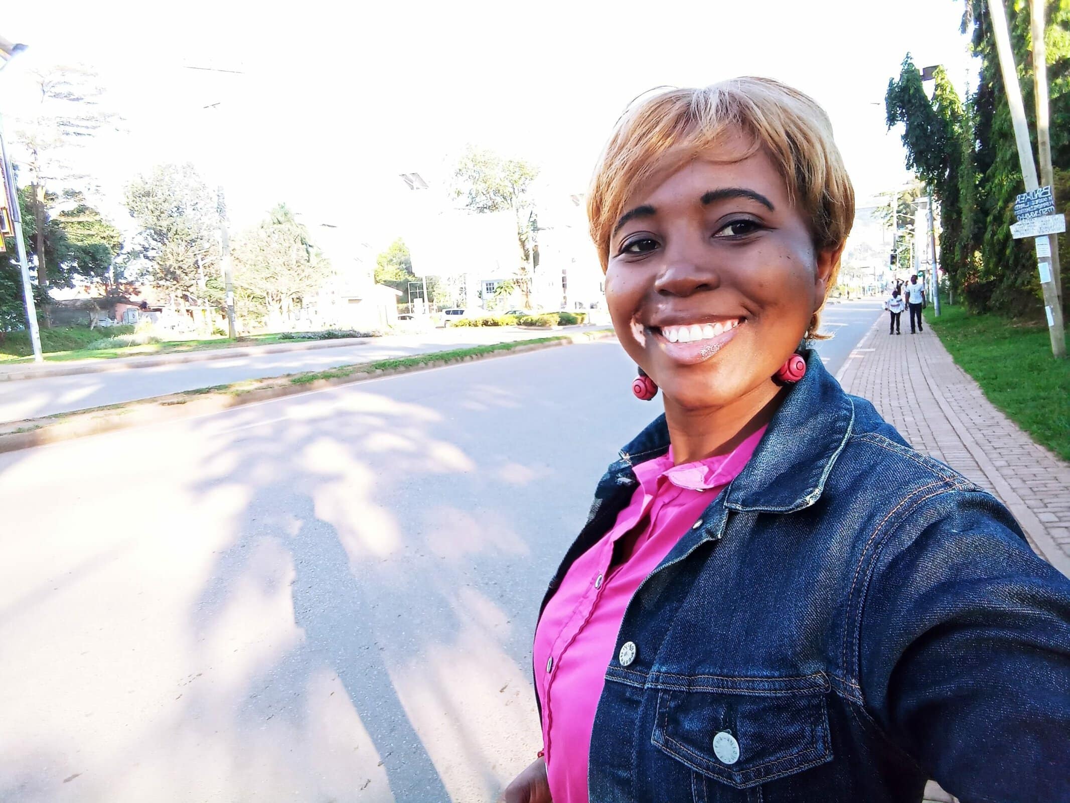Woman smiling on a sunny street, showcasing confidence and positivity.