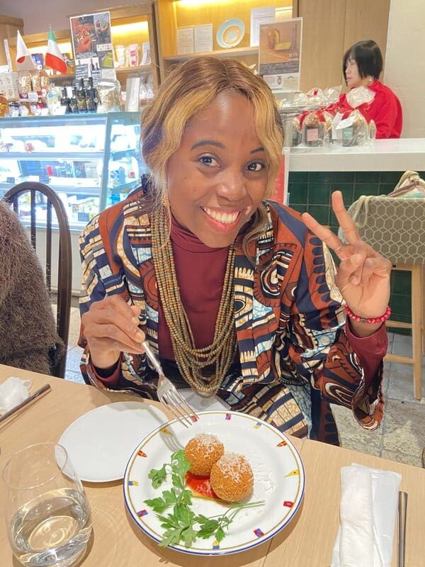 Sarah sitting at a table inside an Italian restaurant and smiling while enjoying a meal.