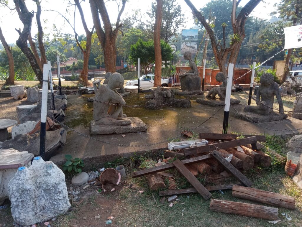 Traditional stone statues displayed in the lush, peaceful courtyard of the Uganda Museum in Kampala.