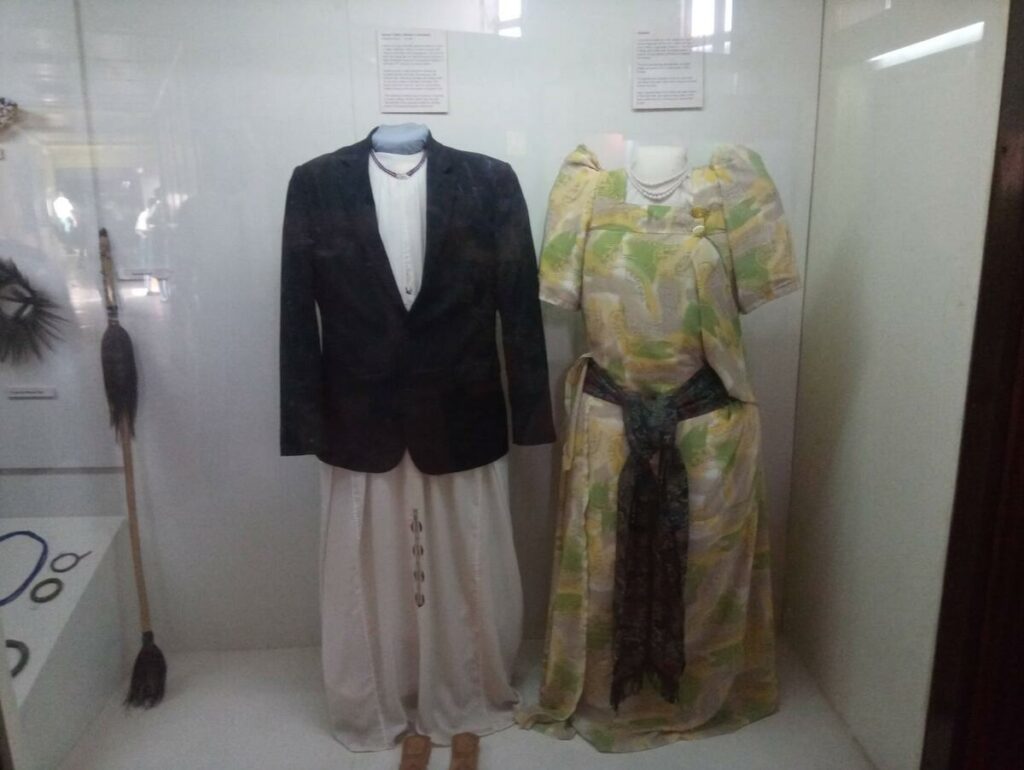 A display at the Uganda Museum featuring traditional Ugandan clothing, including a formal jacket and a colorful patterned garment.