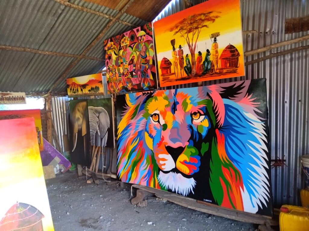 Vibrant, hand-painted canvases of a lion’s face and Kenyan wildlife displayed at an open-air roadside art stall in Diani Beach.