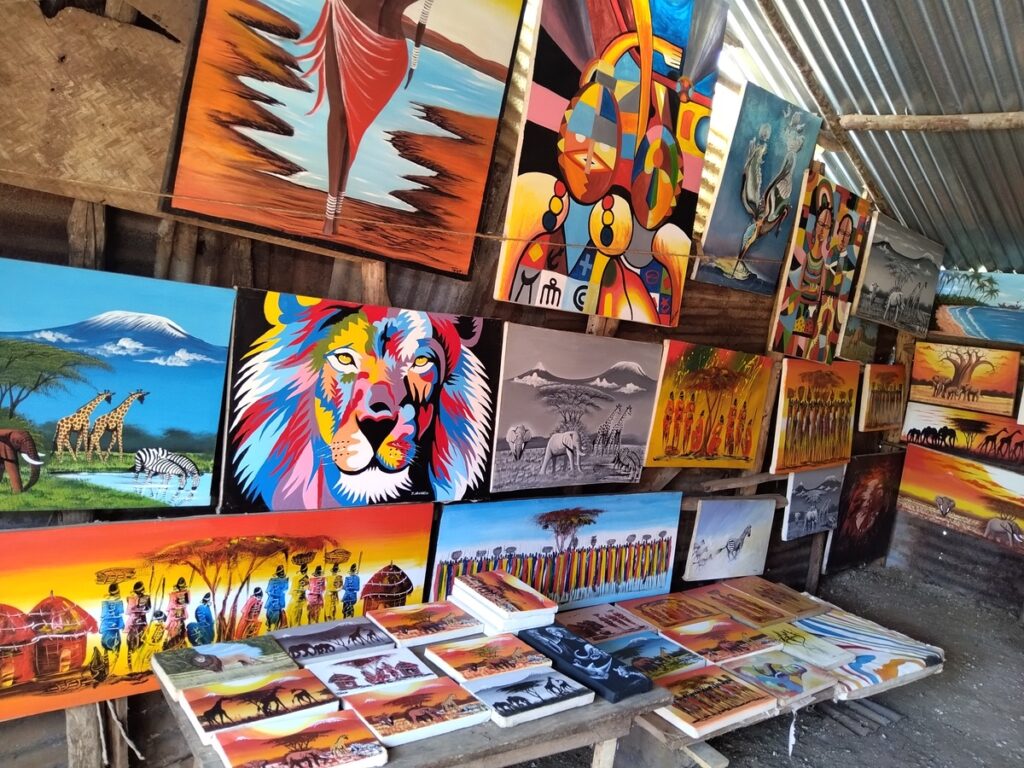 A collection of hand-carved wooden sculptures, including animal figures and decorative bowls, displayed for sale at an open-air Diani Beach craft stal